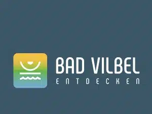Logo für „Bad Vilbel Entdecken“ auf blaugrauem Hintergrund. Das Symbol zeigt einen Farbverlauf in Gelb, Grün und Blau mit einer stilisierten Sonne über Wellen – perfekt für „Wandern nahe Frankfurt“. Der Text „BAD VILBEL ENTDECKEN“ ist in einer modernen, abgerundeten Schriftart gehalten.